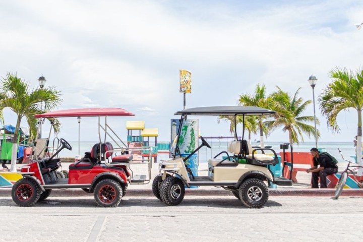 a man riding a horse drawn carriage in front of a truck